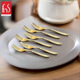 A set of six stainless steel dinner forks with black heads and geometric-patterned handles, arranged neatly on a white napkin surrounded by bowls of berries.